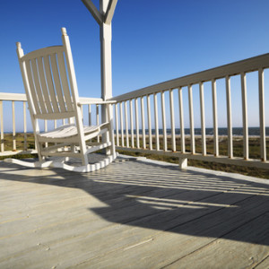 Rocking chair on porch with railing overlooking beach at Bald Head Island, North Carolina.
